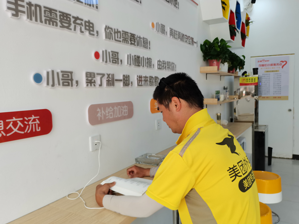 一位&ldquo;外賣小哥&rdquo;正一邊閱讀一邊給手機充電。句容市文體廣電和旅游局供圖