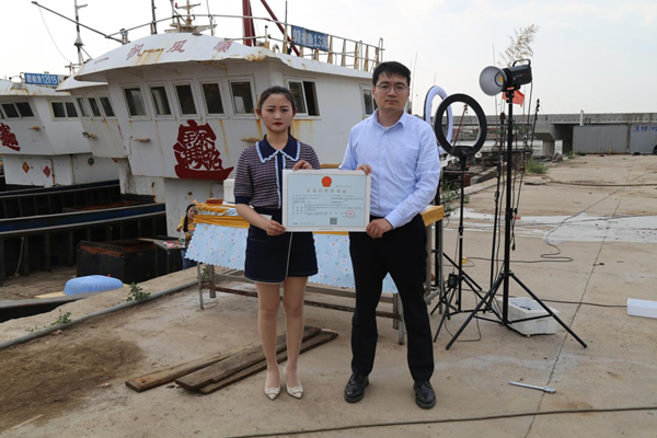 海鮮電商張夢(mèng)琴與幫辦員手持食品經(jīng)營(yíng)許可證合影。贛榆區(qū)委宣傳部供圖