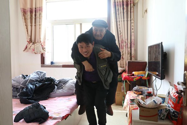 攝影志愿者張建兵背起老黨員到客廳拍攝。受訪者供圖