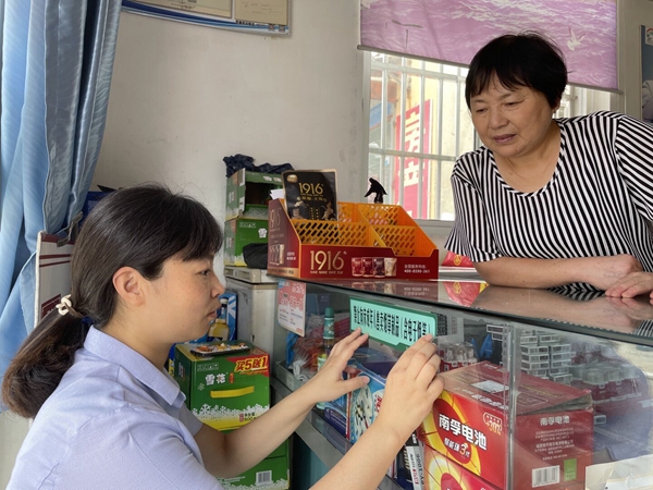 工作人員粘貼新的禁止向未成年人售賣煙草制品警示標識。寶應煙草供圖