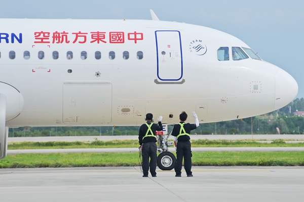 起飛前工作人員向機(jī)組和旅客揮手致意。張旭攝