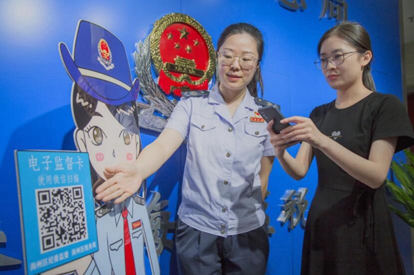 稅務(wù)干部引導(dǎo)納稅人通過“電子監(jiān)督卡”評(píng)價(jià)稅務(wù)部門的退稅減稅服務(wù)。李杰攝