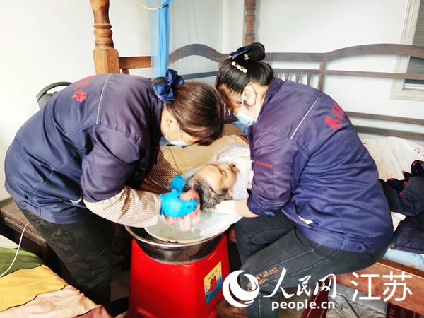 “90后”護理員楊杰（右）與同事為92歲的失能老人朱秀蘭護理。人民網(wǎng)記者 王繼亮攝