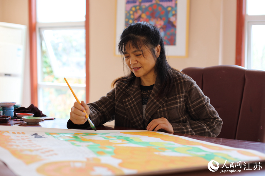  農(nóng)民畫畫家為作品上色。人民網(wǎng) 冷金明攝