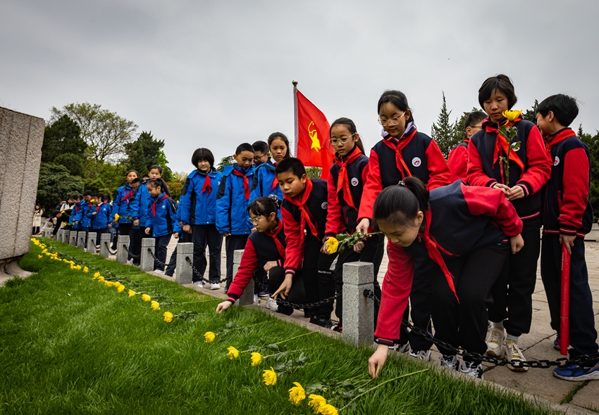 參加祭掃儀式的學(xué)生向烈士墓獻(xiàn)花。胡瀟攝 