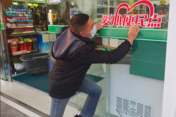 先鋒隊隊員幫助客戶張貼“愛心便民點”標識。寶應(yīng)煙草供圖