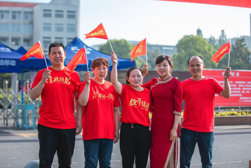 江蘇省泗洪中學(xué)南門口送考點，身穿紅衣的家長們?yōu)榭忌鷤兗佑?。李文攝