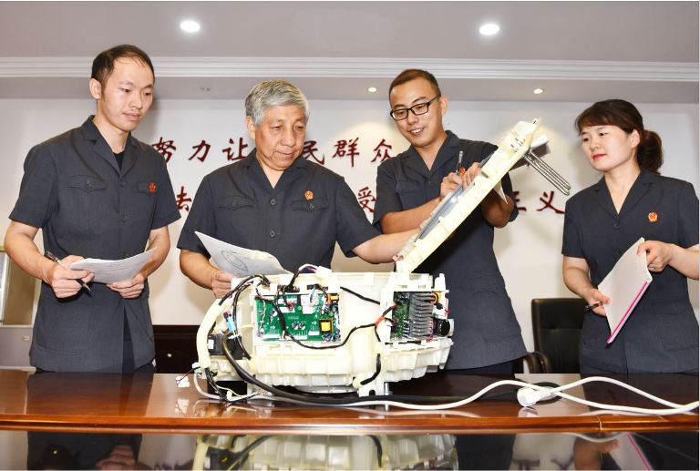 技術(shù)調(diào)查官張耀超（左一）和李偉（右二）輔助主審法官在進(jìn)行技術(shù)比對。徐高純攝