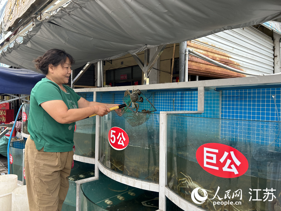 河蟹交易市場(chǎng)內(nèi)經(jīng)營(yíng)戶撈起一籠蟹。人民網(wǎng) 王丹丹攝