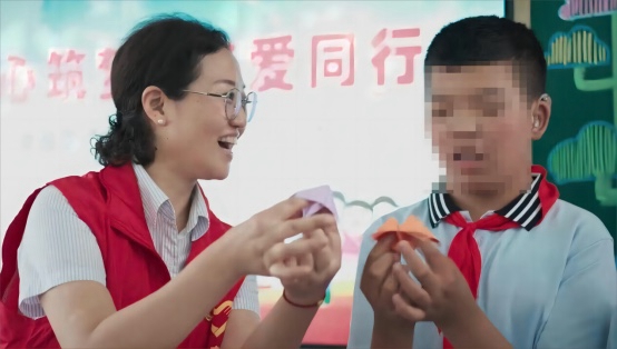 黨員志愿者夏娟與特殊兒童一起折紙。江都煙草供圖
