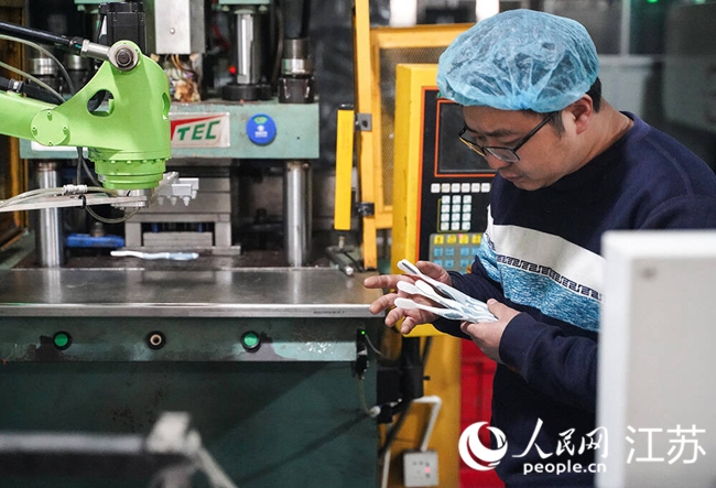 半自動化產(chǎn)線上，技術(shù)人員正在檢查機器注膠的效果。人民網(wǎng) 郜超攝