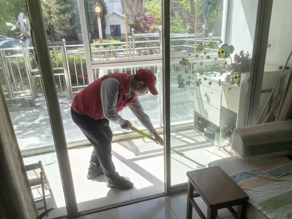 志愿者為老人打掃走廊。張祖權(quán)攝