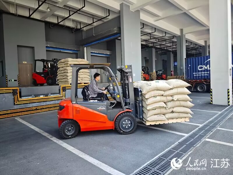 亞太咖啡生豆分撥中心內(nèi)工人將咖啡生豆裝車，準備送往當(dāng)?shù)睾姹浩髽I(yè)。人民網(wǎng) 徐晨曦攝