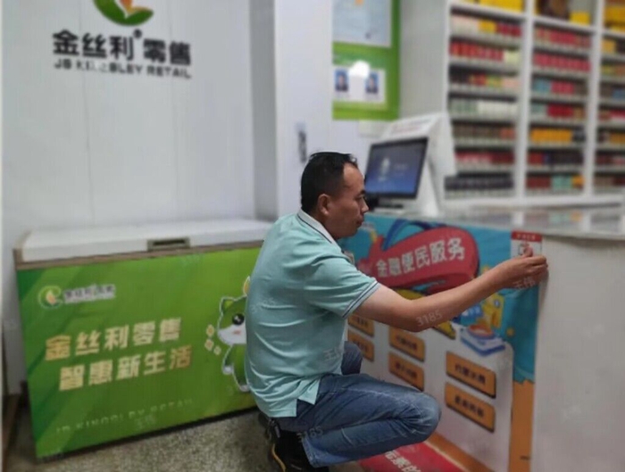 客戶經(jīng)理在改造后的小村小店張貼金融便民服務(wù)宣傳標(biāo)語(yǔ)。尹屾攝