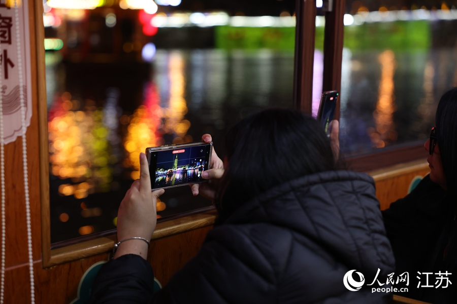 一位記者用手機(jī)抓拍運(yùn)河夜景。人民網(wǎng) 李昱辰攝