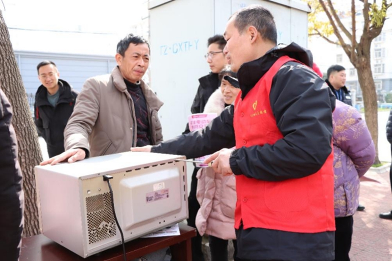 志愿者幫助社區(qū)群眾修理家電。泰州煙草供圖