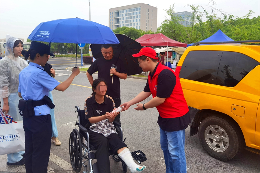 志愿者為行動(dòng)不便的考生遞上礦泉水。王勇攝