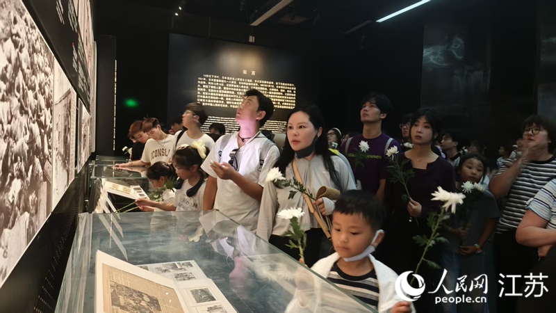 人們手持菊花參觀“南京大屠殺史實(shí)展”。人民網(wǎng) 王丹丹攝