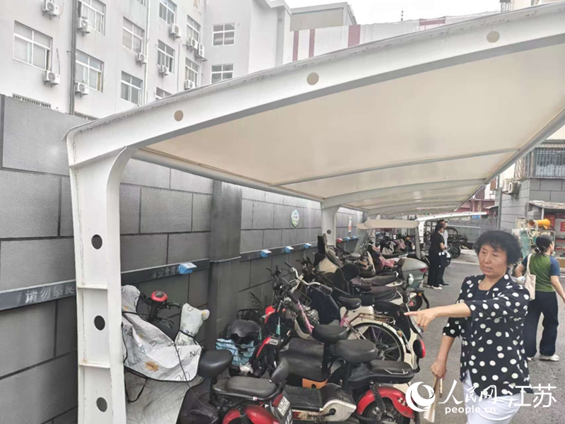 王立華為記者展示小區(qū)內(nèi)新增的車(chē)棚和充電樁。