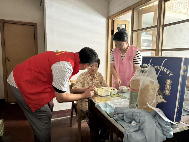 志愿者徐聲凱為邵桂芬送上午餐。柏敏卿攝