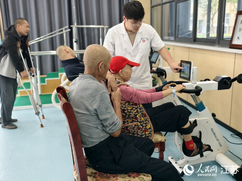 康復(fù)治療師沈陽(yáng)正在協(xié)助老人做康復(fù)訓(xùn)練。人民網(wǎng)記者 馬曉波攝