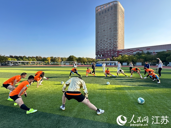 混編友誼賽前，“蘇超”南京隊(duì)球員與媒體人進(jìn)行熱身。人民網(wǎng) 王純攝