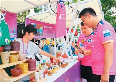 “蘇超”鎮(zhèn)江球迷購買“非遺”文創(chuàng)產(chǎn)品。  江蘇省文化和旅游廳供圖