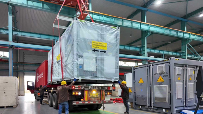 在工作人員指揮下，儲能一體機(jī)穩(wěn)穩(wěn)放在等待“出?！卑l(fā)運的重卡上。受訪者供圖