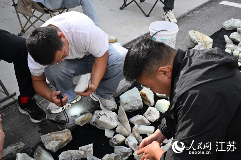 玉石原石交易區(qū)，玉石買家正在查看玉石質(zhì)量。人民網(wǎng)記者張瀚天攝