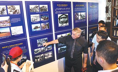 格林（左二）在長(zhǎng)汀舉辦的飛虎隊(duì)主題歷史圖片展上講述歷史照片背后的故事。本報(bào)記者 鐘自煒攝