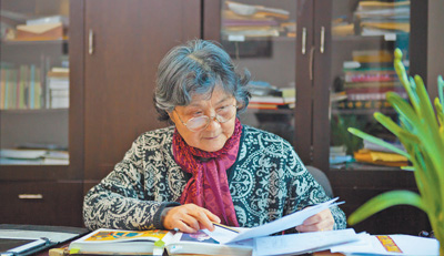 圖為錢小萍正在審閱設(shè)計稿。受訪者供圖