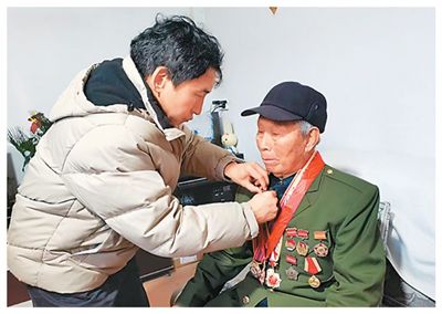 郭宏偉（左）在為抗戰(zhàn)老兵整理衣裝。王保軍攝